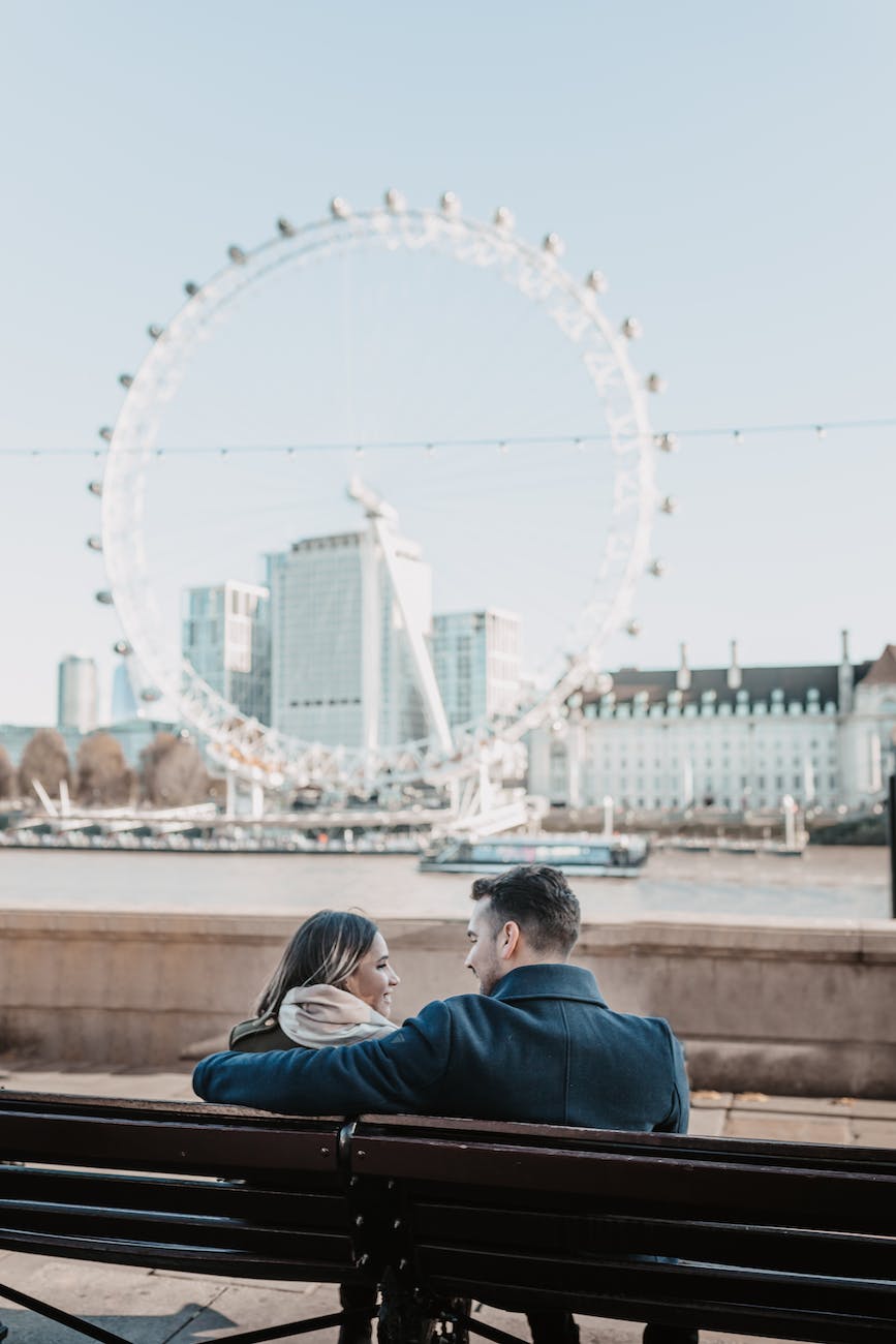 couple sitting on a bench with a view on london eye