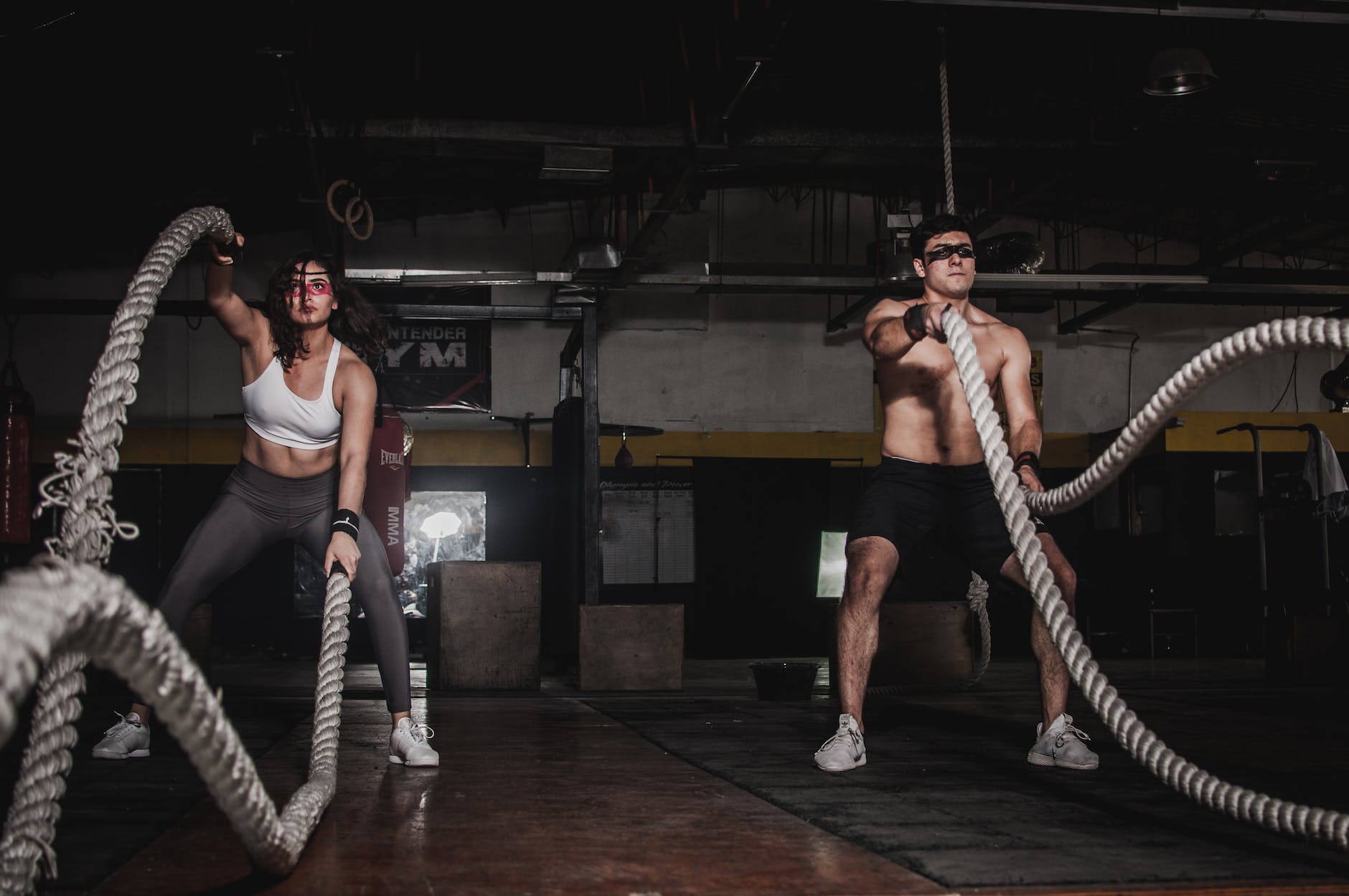 man and woman holding battle ropes