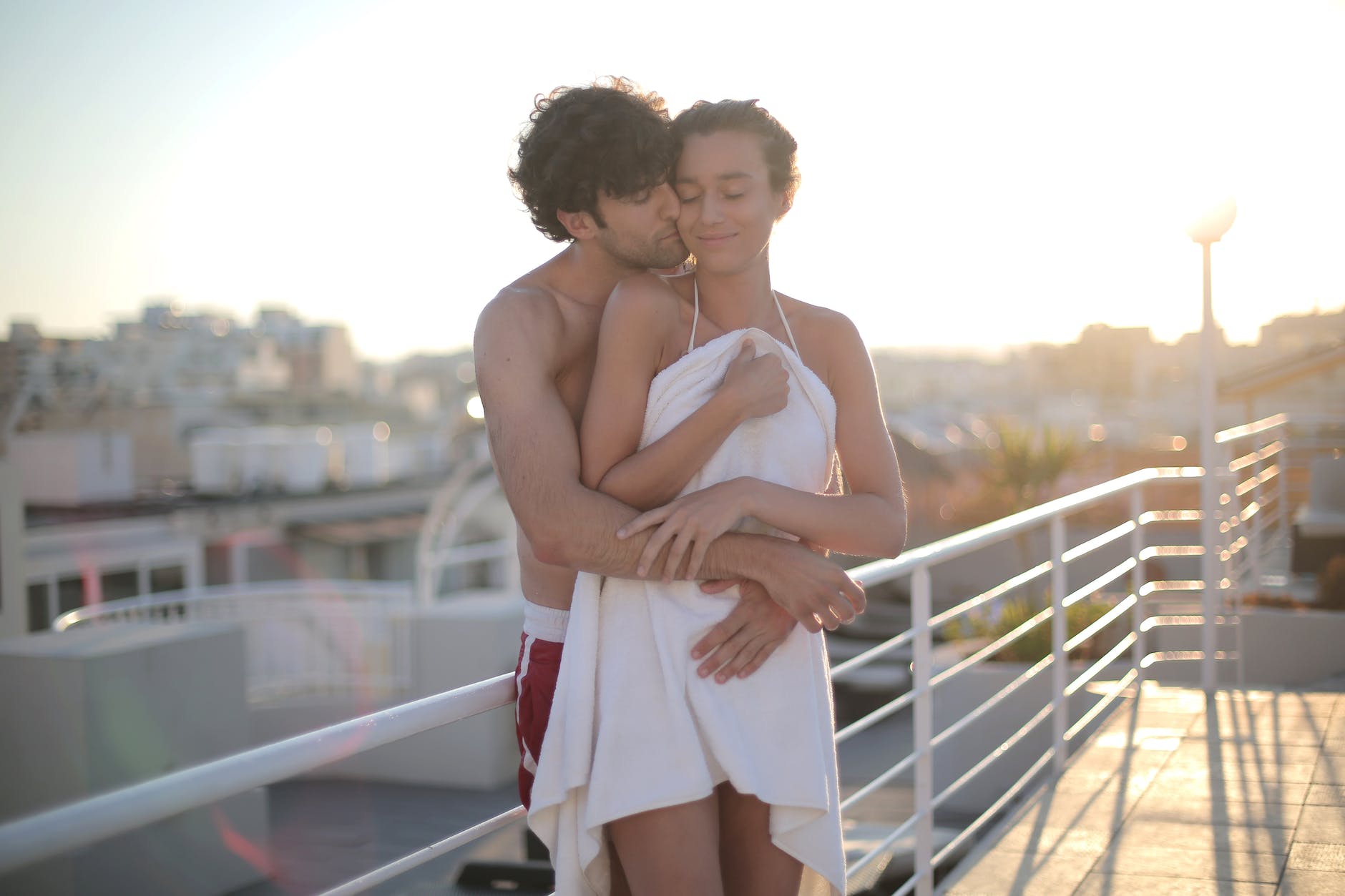 happy lovers embracing on rooftop after swimming during sunset