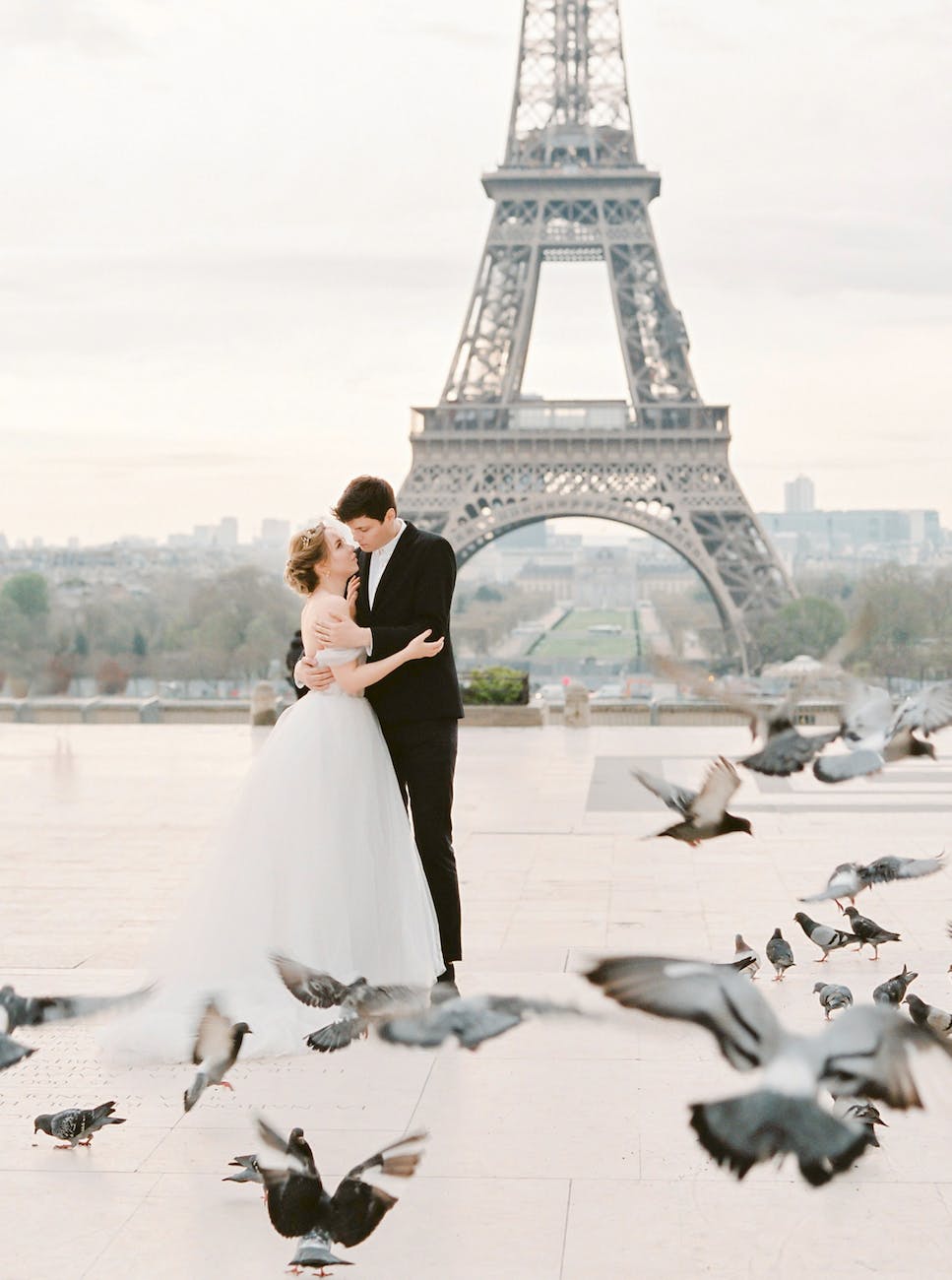 pigeons around newlyweds standing with eiffel tower behind