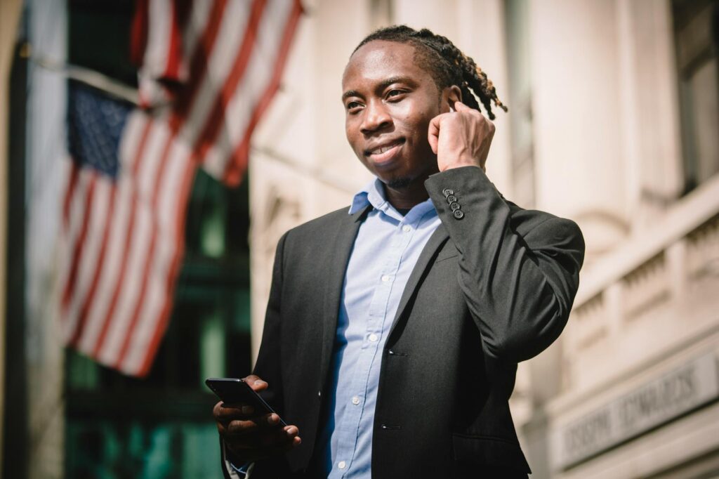 positive young entrepreneur listening to music through earphones on street