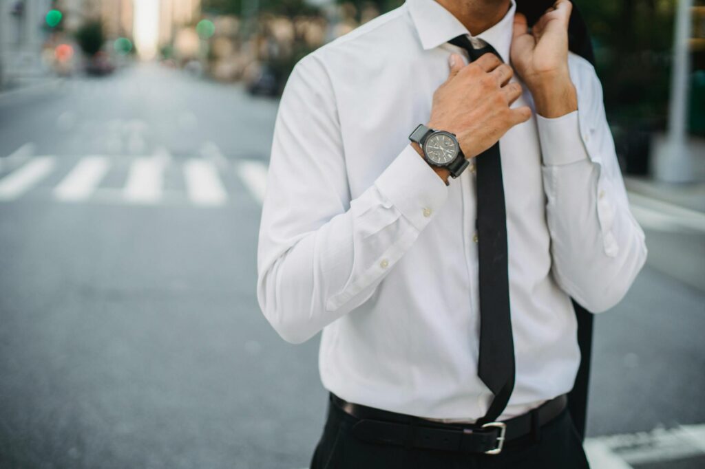 unrecognizable man correcting tie in street