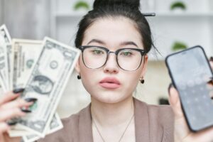 a woman holding an iphone and cash money